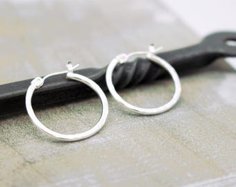 May include: A pair of silver hoop earrings with a hammered finish. The earrings are simple and elegant.