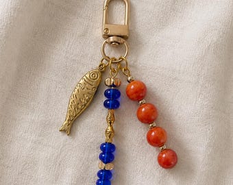 Llavero colorido con cuentas de vidrio naranja y dije de sardina dorada, dije para bolso con temática costera y marina, llavero para bolso de playa