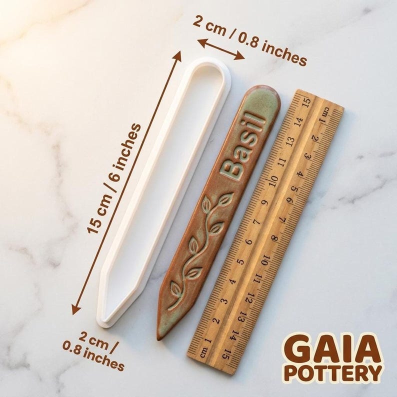 Size reference for Gaia Pottery herb marker clay cutter showing 15cm length and 2cm width beside a finished Basil ceramic marker and wooden ruler for scale