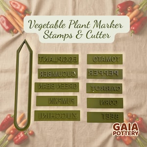 May include: A collection of green vegetable plant marker stamps and a cutter. The stamps are labelled with names such as "Tomato", "Cucumber", and "Carrot". The text "Vegetable Plant Marker Stamps & Cutter" is at the top. The GAIA POTTERY logo is at the bottom right.