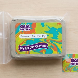 May include: A block of grey air dry clay from Gaia Pottery, labelled "Premium Air Dry Clay" and "DIY Air Dry Clay Kit". The label features a colourful swirl design. A small business card with the Gaia Pottery logo is also present.