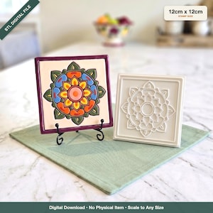 May include: A square tile stamp measuring 12cm x 12cm, featuring a central mandala design. One version is displayed on a black metal stand with a colorful painted pattern of orange, yellow, blue, and green, while the other is a plain white relief.