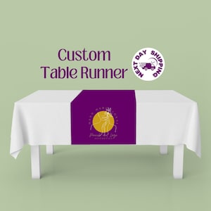 May include: Purple table runner with a gold and white floral design. The design features a circle with the text "Hand Made Floral" and "Flourished and Large AESTHETICS".