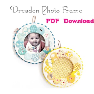May include: Two handmade Dresden photo frames, one with a blue and white floral design and a baby photo inside, and the other with a yellow and white floral design. Both frames have a scalloped edge and a loop for hanging.