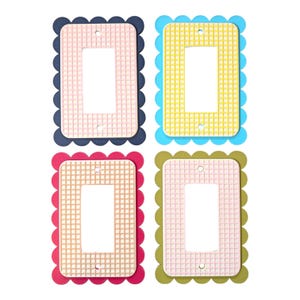 Puede incluir: Cuatro cubiertas de interruptores de luz coloridas. Cada cubierta tiene un borde festoneado y una abertura rectangular. Los colores incluyen rosa con azul marino, amarillo con turquesa, rosa con rojo y rosa con verde oliva. Las cubiertas tienen un patrón de cuadrícula.