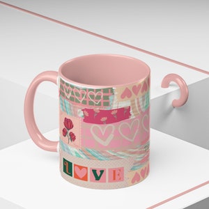Puede incluir: Taza de cerámica rosa con un diseño de patchwork con corazones, flores y la palabra "LOVE" en letras de colores.