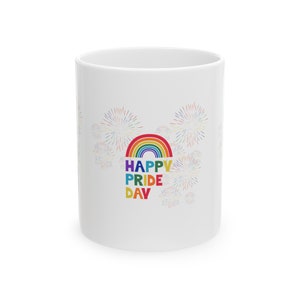 May include: White ceramic mug with a rainbow and the text "HAPPY PRIDE DAY" in colorful letters. The background features a pattern of fireworks.