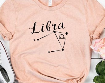 May include: A light pink t-shirt with the word "Libra" and a constellation design in black.
