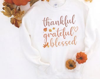 May include: White sweatshirt with the text "thankful grateful blessed" in pink and orange lettering with small leaf graphics.