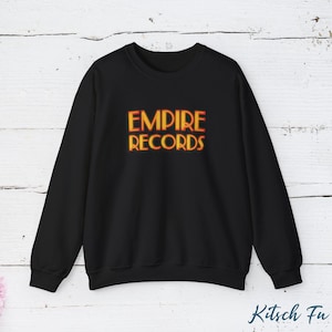 May include: Black crewneck sweatshirt with the text "EMPIRE RECORDS" in orange and yellow lettering. The sweatshirt is a long-sleeved top, perfect for casual wear. The design is centered on the chest.