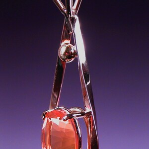 May include: A delicate gold pendant necklace with a heart-shaped bail and a large oval-shaped orange gemstone.