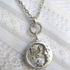 May include: A silver necklace with a crescent moon pendant featuring a visible clockwork mechanism. The pendant has a star and the text "Waltham ST 20" on it.