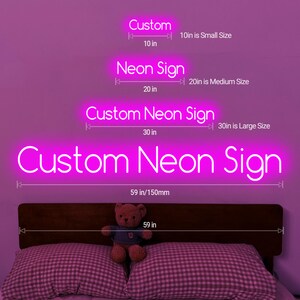 K&ouml;nnte beinhalten: Ein leuchtend pinkfarbenes Neon-Schild mit der Aufschrift "Custom Neon Sign". Das Bild zeigt verschiedene Gr&ouml;&szlig;en: 25 cm, 50 cm, 76 cm und 150 mm. Ein Teddyb&auml;r sitzt auf einem Bett mit karierten Kissen.