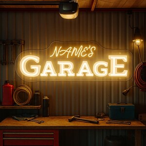 K&ouml;nnte beinhalten: Ein Neonschild mit der Aufschrift "NAME'S GARAGE" in einem Retro-Schriftstil, montiert an einer Wellblechwand. Das Schild leuchtet warm und einladend. Die Garage umfasst Werkzeuge, eine Werkzeugkiste und eine Werkbank.