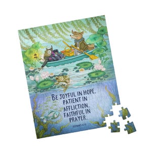 Op de afbeelding: Een kleurrijke legpuzzel met een geïllustreerde scène van dieren in een boot op een vijver, met waterlelies en vissen. De puzzel bevat de tekst "BE JOYFUL IN HOPE, PATIENT IN AFFLICTION, FAITHFUL IN PRAYER. ROMANS 12:12".