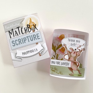 Könnte beinhalten: Zwei offene Streichholzschachtel-Skripturkarten. Auf einer steht "MATCHBOX SCRIPTURE" und "PHILIPPIANS 1:3". Die andere zeigt eine Cartoon-Maus mit dem Text "THANK YOU GOD!" und "YOU ARE LOVED!" vor einem floralen Hintergrund.
