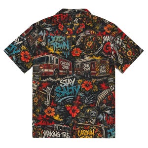 May include: Short-sleeved button-down shirt with a vibrant, all-over print. The design features fire trucks, graffiti, hibiscus flowers, and skeleton figures. Text includes "Job Town," "Stay Salty," and "Catchin Jobs." The shirt is predominantly black with red, orange, and blue accents.