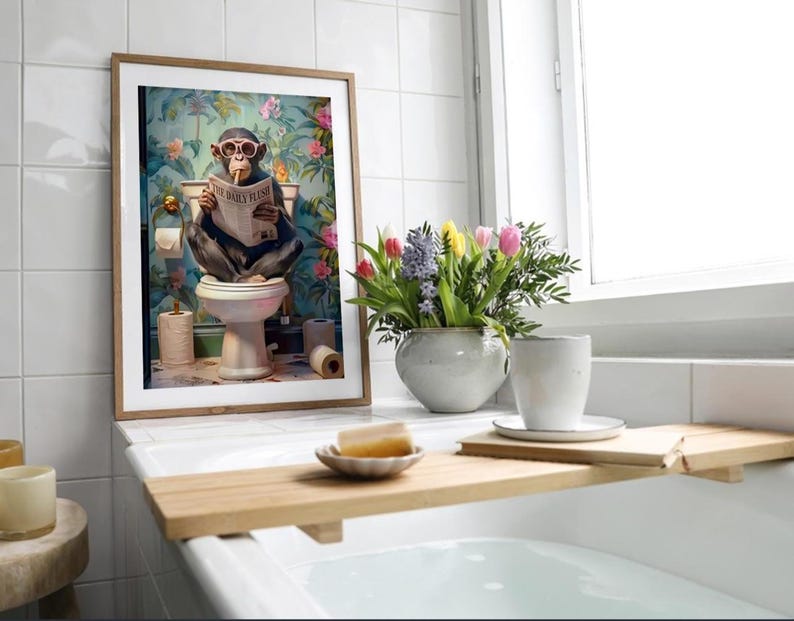 May include: A framed wall art print featuring a chimpanzee wearing pink sunglasses while sitting on a toilet and reading a newspaper titled The Daily Flush, set against a vibrant floral wallpaper background with rolls of toilet paper.