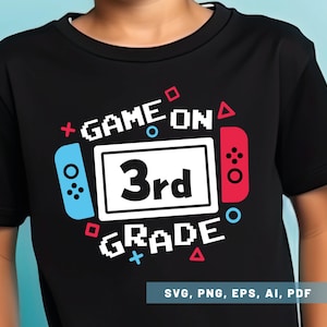 May include: Black t-shirt with a graphic design featuring the words "GAME ON 3rd GRADE" in white pixelated font. The design includes a game controller illustration in red and blue, with additional geometric shapes.
