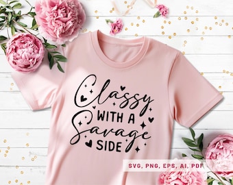 May include: Light pink t-shirt with the phrase "Classy with a Savage Side" in black script. The design includes hearts and stars. The shirt is surrounded by pink flowers and greenery.