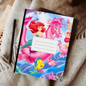 Puede incluir: Un cuaderno colorido con Ariel de La Sirenita. La portada presenta a Ariel, un caballito de mar rosa y otros personajes de la pel&iacute;cula. Incluye una etiqueta blanca con l&iacute;neas para escribir.