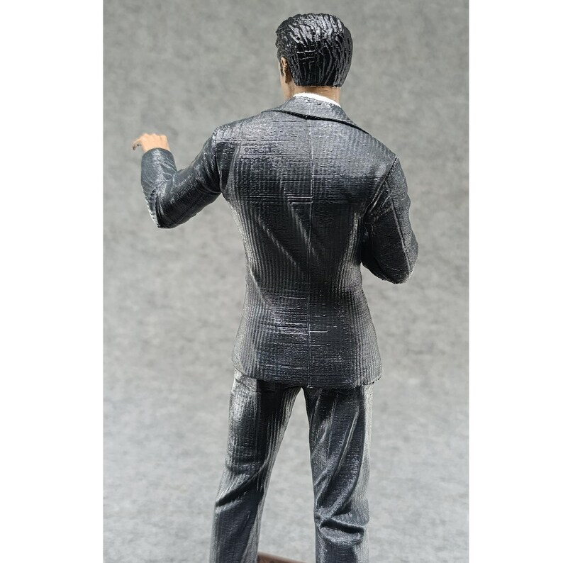 May include: A black and gray striped suit with a single-breasted jacket and matching pants. The suit is made of a textured fabric and has a classic fit.