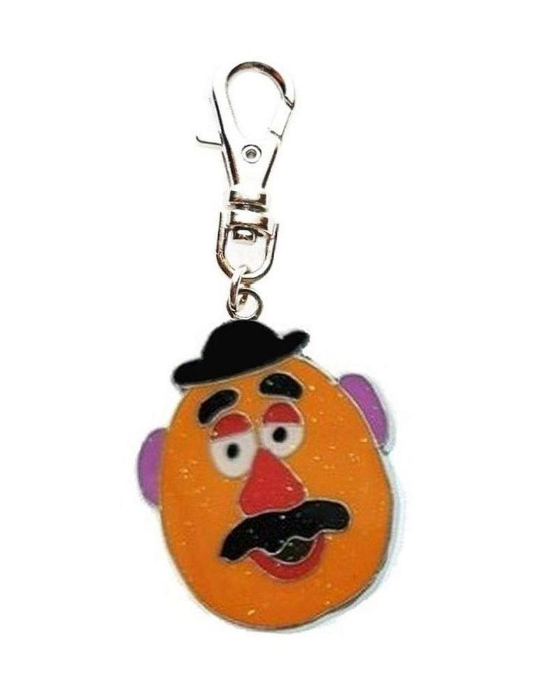 K&ouml;nnte beinhalten: Ein silberner Schl&uuml;sselanh&auml;nger mit einem Cartoon-Mr. Potato Head mit schwarzem Hut, orangefarbenem Gesicht, lila Ohren, roter Nase und schwarzem Schnurrbart.