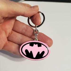 Llavero con dije de superhéroe de murciélago rosa, símbolo de libro, llavero, anillo o bolso, mochila, chaqueta, bolso de mano, bolso de pañales, billetera, etc.