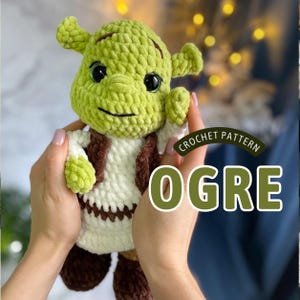 May include: A handmade green crochet ogre doll with black eyes, a stitched smile, and small ears. The ogre wears a white shirt, brown vest, and brown shoes. The text "CROCHET PATTERN OGRE" is visible.