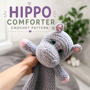 May include: A crocheted hippo comforter in soft gray yarn with pink accents on the ears and feet. The hippo has large, expressive eyes and is held up in front of a gray background. Text on the image reads "HIPPO COMFORTER CROCHET PATTERN."