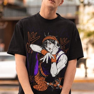 Może przedstawiać: Czarny T-shirt z nadrukiem graficznym postaci z kresk&oacute;wki z pomarańczowymi włosami i fioletową koszulą. Postać trzyma rękę przy twarzy i ma zaskoczony wyraz twarzy. Grafika jest otoczona czarnymi i białymi liniami.