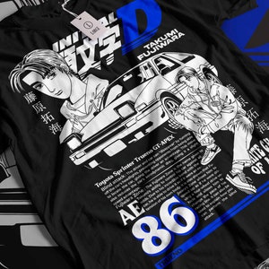 Peut inclure: T-shirt noir avec un imprimé graphique blanc d'une voiture, d'un conducteur et de texte qui dit "Initial D", "Takumi Fujiwara", "Toyota Sprinter Trueno GT-APEX", "AE86", "Trueno", et "White Ghost of Akina".