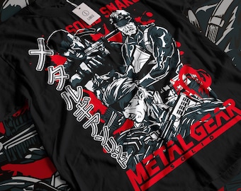 May include: Black t-shirt with a graphic of Solid Snake from the Metal Gear Solid video game. The graphic features Solid Snake holding a gun and the text "Solid Snake" and "Metal Gear Solid" in red.