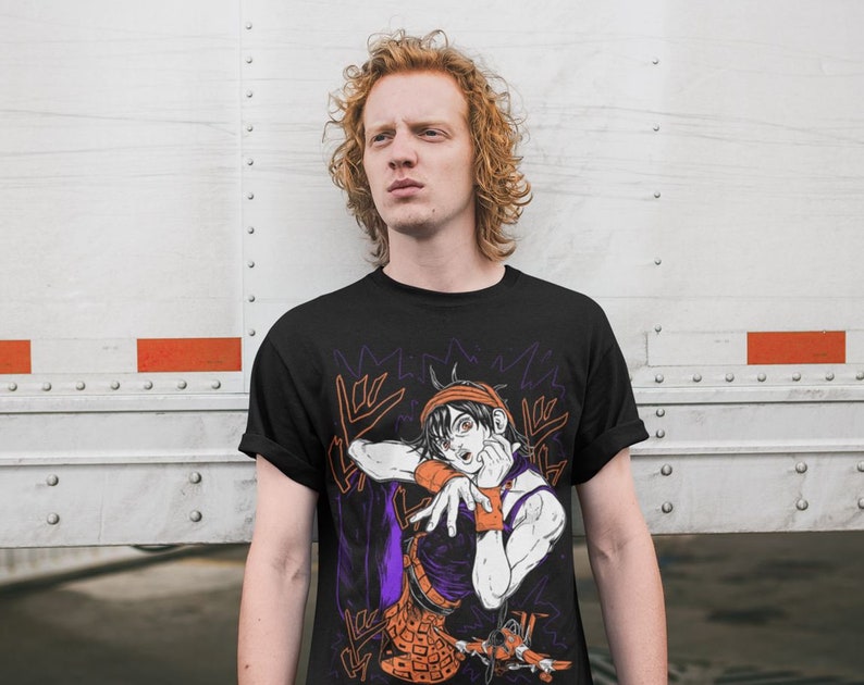 Może przedstawiać: Czarny T-shirt z nadrukiem graficznym postaci z kresk&oacute;wki w pomarańczowych i fioletowych ubraniach. Postać wykonuje gest ręką. Na koszulce widoczny jest napis "Giorno Giovanna".