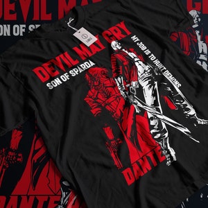 Könnte beinhalten: Schwarzes T-Shirt mit einer roten und weißen Grafik eines Videospielcharakters, dem Text "Devil May Cry", "Son of Sparda" und "My job is to hunt demons" sowie dem Namen des Charakters "Dante".