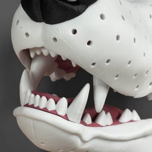 May include: A 3D printed white animal sculpture featuring a black nose and an open mouth with visible white teeth and pink gums. The surface of the sculpture is covered in a uniform pattern of small circular holes, showing a layered texture.