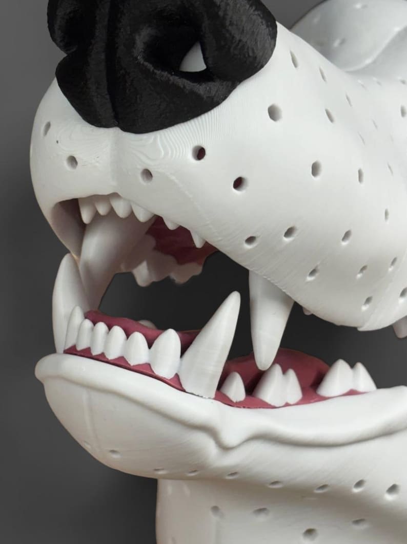 May include: A 3D printed white animal sculpture featuring a black nose and an open mouth with visible white teeth and pink gums. The surface of the sculpture is covered in a uniform pattern of small circular holes, showing a layered texture.