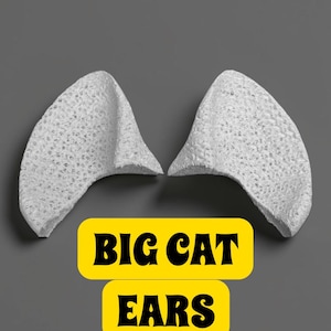 May include: Two white, textured cat ears are displayed against a gray background. The ears are made of a porous material and are positioned to appear as if they are worn on the head. Text in a yellow box reads "BIG CAT EARS."