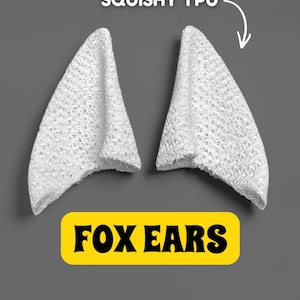 May include: Two white, textured fox ears made of squishy TPU material. The ears are triangular in shape and are displayed against a gray background. The text "FOX EARS" is in a yellow rectangle below the ears.