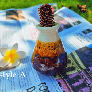May include: A brown and white ceramic vase with a brown pine cone on top. The vase is sitting on a newspaper with the word "Today" printed on it.
