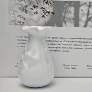 May include: White ceramic vase with a textured, crumpled design. The vase has a wide opening and a rounded bottom.