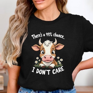 Könnte beinhalten: Schwarzes T-Shirt mit einer Comic-Kuh und dem Text "There's a 99% chance... I don't care".