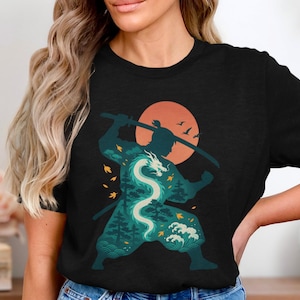 Könnte beinhalten: Schwarzes T-Shirt mit einer Grafik eines Samurai-Kriegers und einem Drachendesign. Der Krieger ist vor einem Sonnenuntergang silhouettiert, mit erhobenem Schwert. Der Drache ist weiß und blaugrün, mit Wald- und Wellendetails.