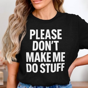 May include: Black t-shirt with the white text "PLEASE DON'T MAKE ME DO STUFF". The shirt is a crew neck style and is made of a soft material. The text is in a bold, sans-serif font.