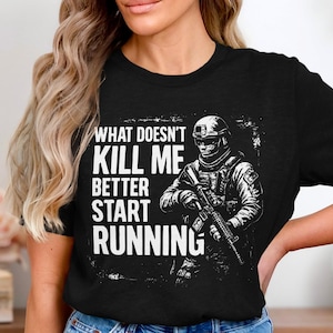 Puede incluir: Camiseta negra con un gráfico desgastado de un soldado con un rifle y el texto "WHAT DOESN'T KILL ME BETTER START RUNNING" en blanco. El soldado lleva un casco y equipo táctico.