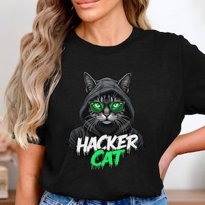 Könnte beinhalten: Schwarzes T-Shirt mit einem Grafikdruck eines Katers, der eine schwarze Kapuze und eine grüne Sonnenbrille trägt. Der Text "Hacker Cat" ist in Grün unter dem Kater geschrieben.