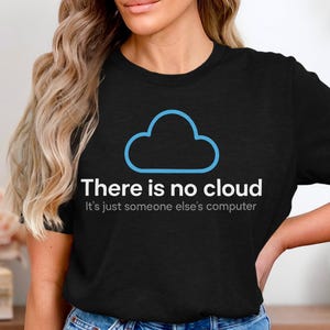 Peut inclure: T-shirt noir avec un nuage bleu et le texte "There is no cloud. It's just someone else's computer." Le t-shirt est fait d'une matière douce.