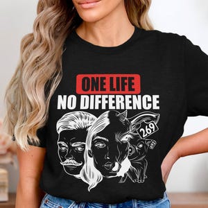 Puede incluir: Camiseta negra con texto blanco que dice "ONE LIFE NO DIFFERENCE". La camiseta presenta una ilustración blanca de un humano, una vaca y un cerdo con los números 269 y 622.