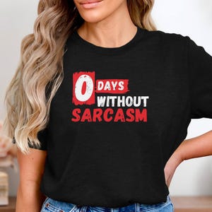 May include: Black t-shirt with red text that says "0 days without sarcasm".
