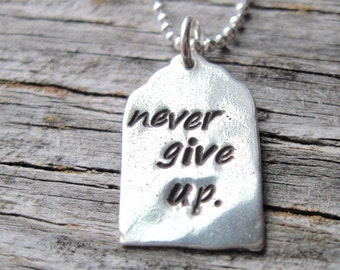 May include: Silver necklace with a tag pendant that says "never give up."